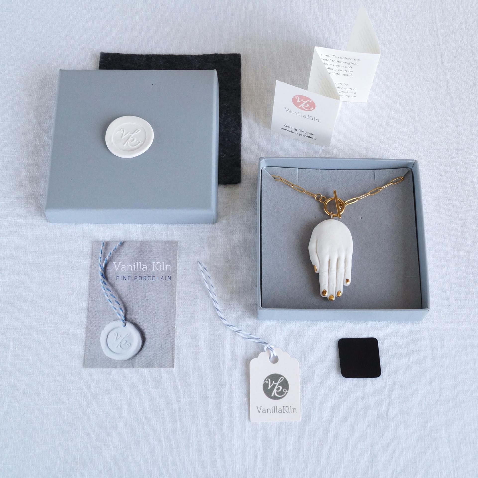 Open gift box, lid and monogram, felt protective cover, care instructions, anti tarnish tab, swing tag and business card.